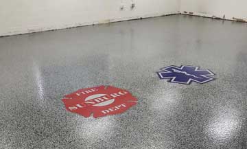 fire and ems logos embeded into gray flake epoxy flooring for local firestation.