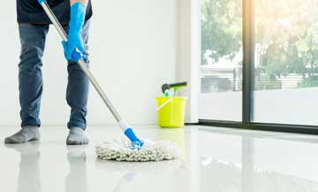 Maid using mop to clean white epoxy floor