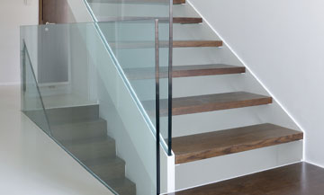 brown epoxy flooring meeting up with modern white and brown staircase in home